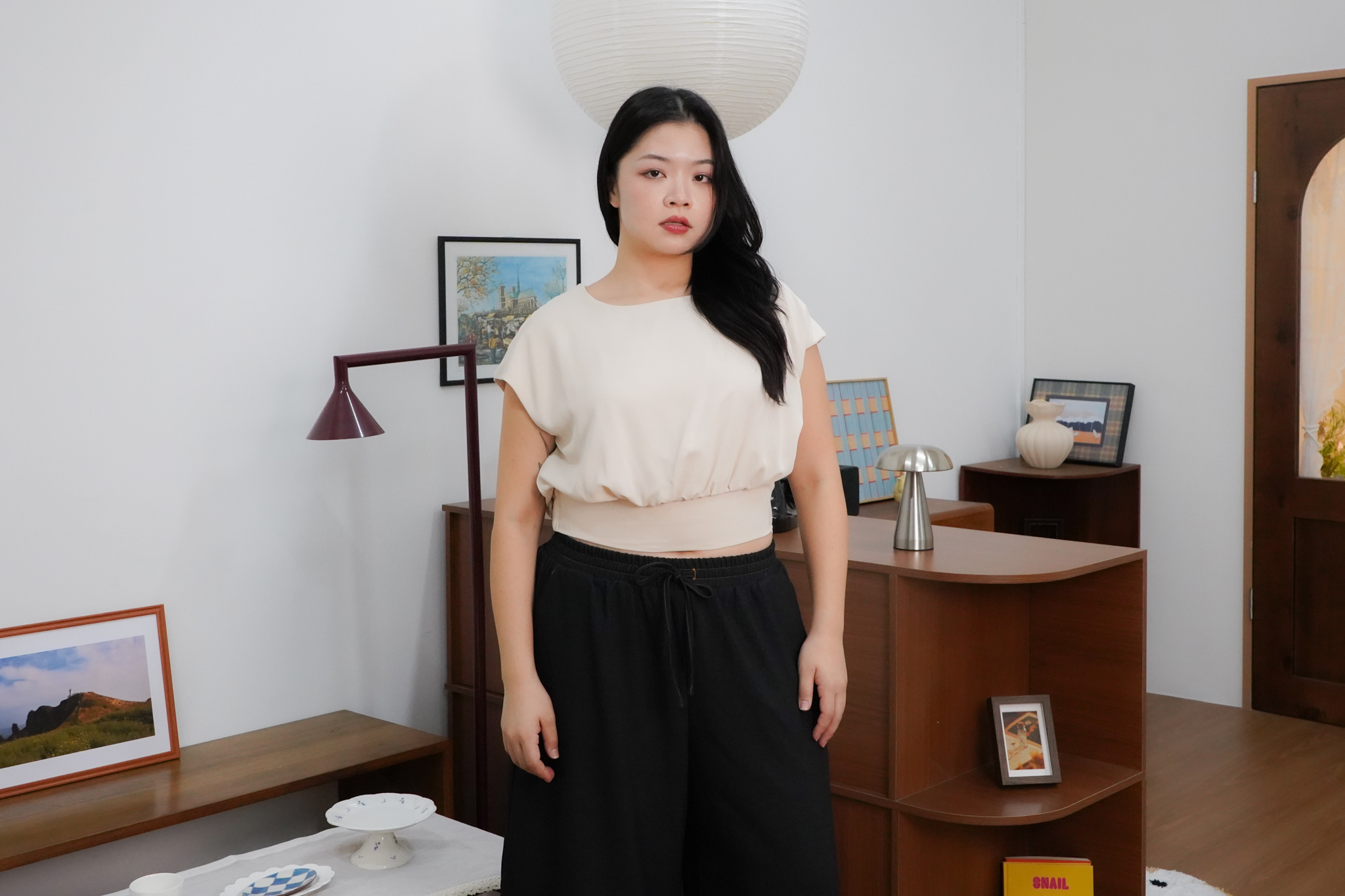 Model wearing a cream top and black trousers from The Fleur Label